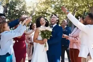 Coppia di sposi sorridenti circondata da invitati durante il lancio dei petali, immortalata in un wedding video ricco di emozione e felicità.